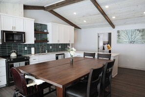 A kitchen with white cabinets, a wooden dining table, and a microwave.