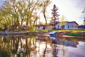 A lakeside property with a dock, a small boat, and a house with a deck.