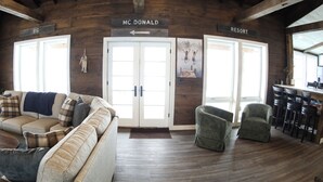 A wooden interior with a sofa, chairs, a bar area, and signs indicating 'MC DONALD' and 'RESORT' directions. - Modern Lakeside Retreat: Ultimate Group Getaway (Dent)
