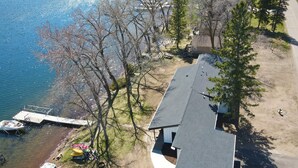An aerial view of a house with a dock, trees, and a clear view of the water. - Modern Lakeside Retreat: Ultimate Group Getaway (Dent)