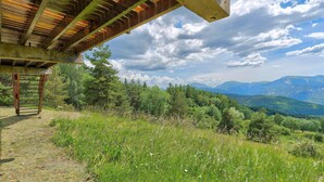 A covered outdoor area with a wooden ladder, surrounded by lush greenery and a mountainous landscape. - Chalet with Mountain Views, Private Garden and Balcony (Seyne)