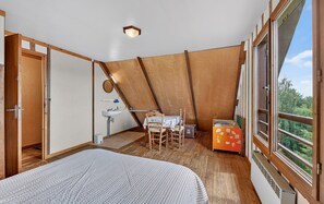 A bedroom with a bed, a small table with a chair, a window, and a view of greenery outside. - Chalet with Mountain Views, Private Garden and Balcony (Seyne)