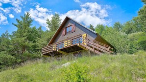 Een houten hut met een balkon, omringd door bomen en gras.