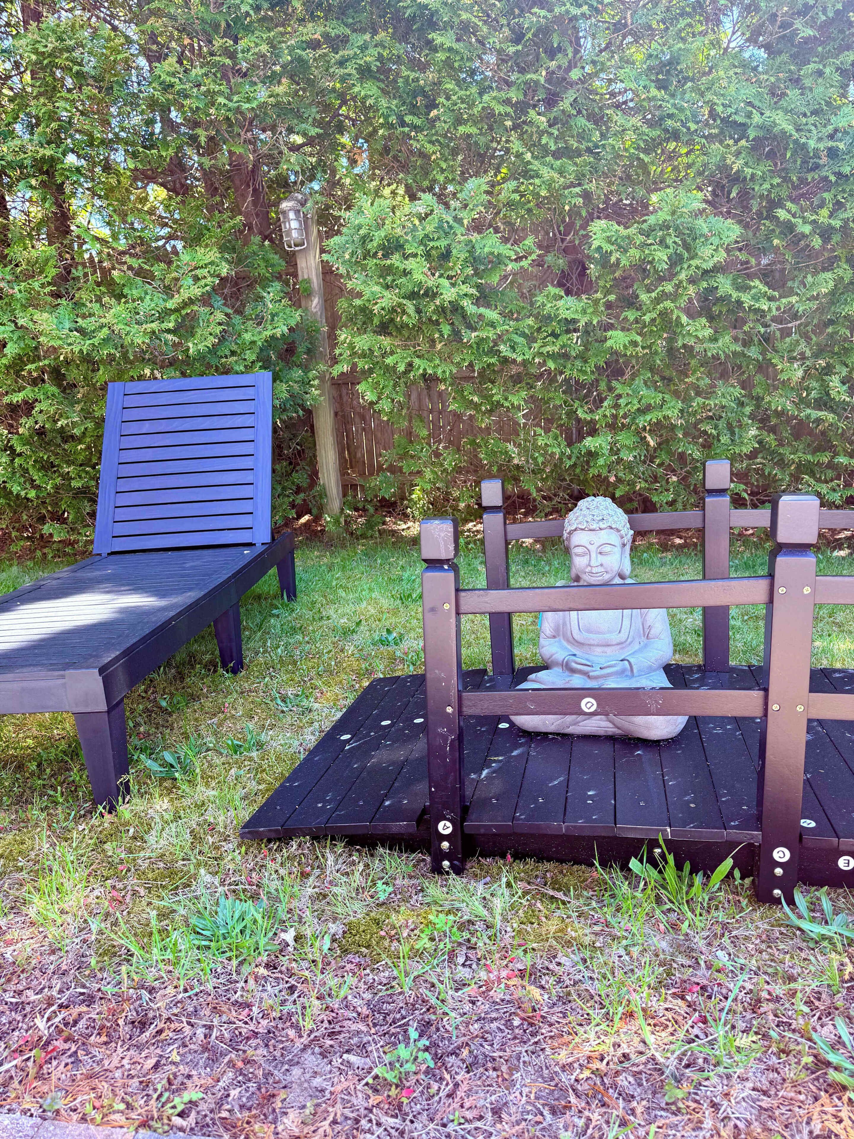Un banc en bois avec une statue au centre, entouré de verdure.