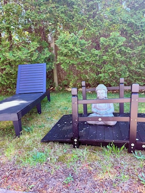 A wooden bench with a statue in the center, surrounded by greenery.