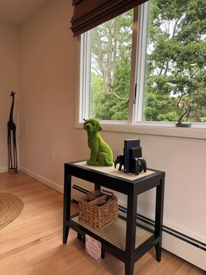 A room with a window, a small table with a basket, a giraffe decoration, and a stuffed animal.
