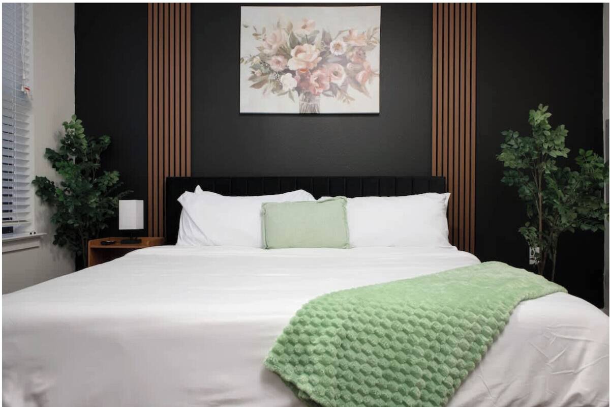 A bedroom with a bed, a nightstand, a lamp, and a painting on the wall.