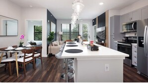 A modern kitchen with a central island, built-in appliances, and a dining area with a table and chairs. - Labor by Stylish Stays (San Antonio)