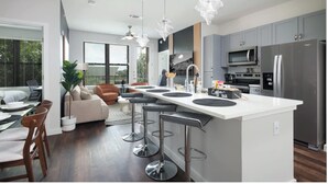 A modern kitchen with a central island, stainless steel appliances, and pendant lighting. - Labor by Stylish Stays (San Antonio)