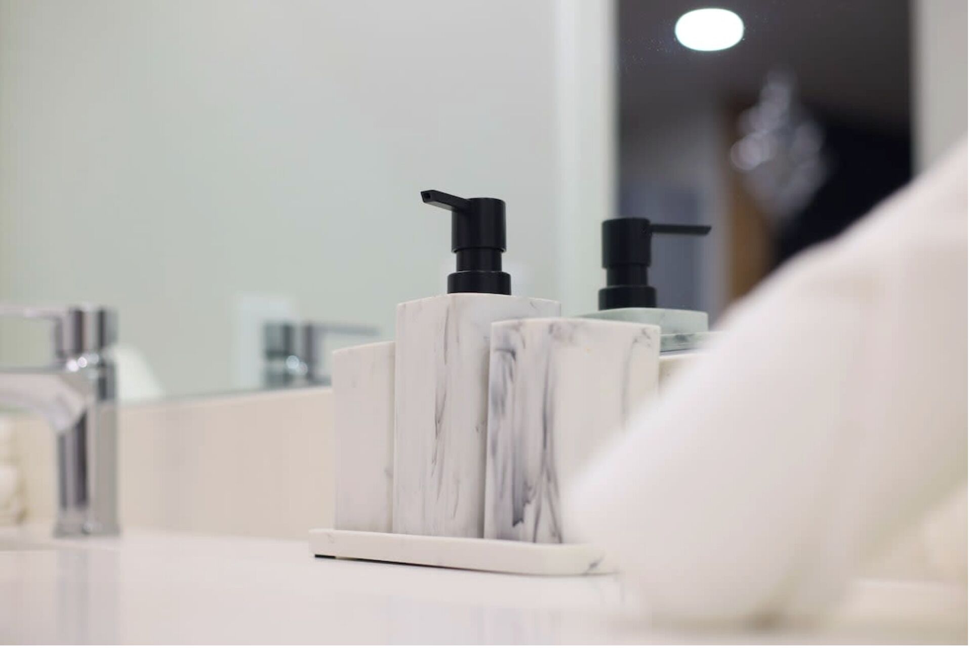 Een badkamer met een marmeren zeepdispenserhouder en een pompdispenser.