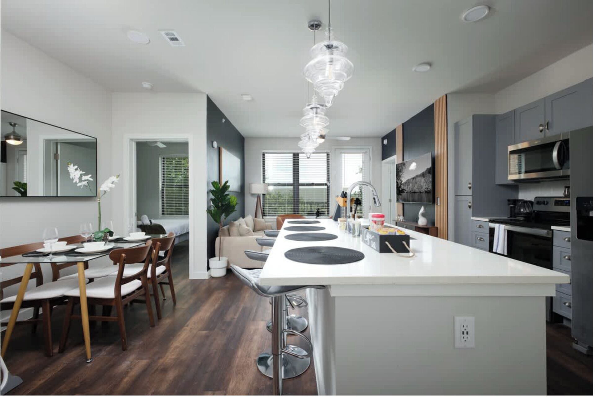 A modern kitchen with a central island, stainless steel appliances, and a dining area with a wooden table and chairs.