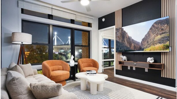 A modern living room with a sofa, two armchairs, a coffee table, and a TV mounted on the wall. - Labor by Stylish Stays (San Antonio)