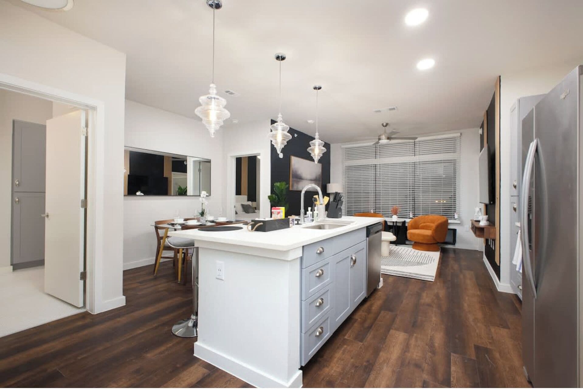 Une cuisine moderne dotée d’un îlot central, de luminaires suspendus et d’un coin repas avec une chaise.