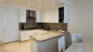 Uma cozinha moderna com armários brancos, bancadas de granito e uma ilha integrada.