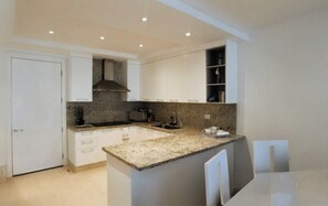 Una cocina moderna con armarios blancos, encimeras de granito y una isla integrada.