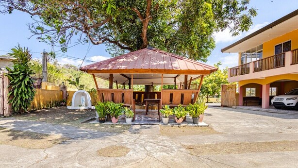 A gazebo with a metal roof, surrounded by potted plants, in a courtyard with a concrete floor. - 3-bedroom estate in serene Calatagan with cool AC breeze (Calatagan)
