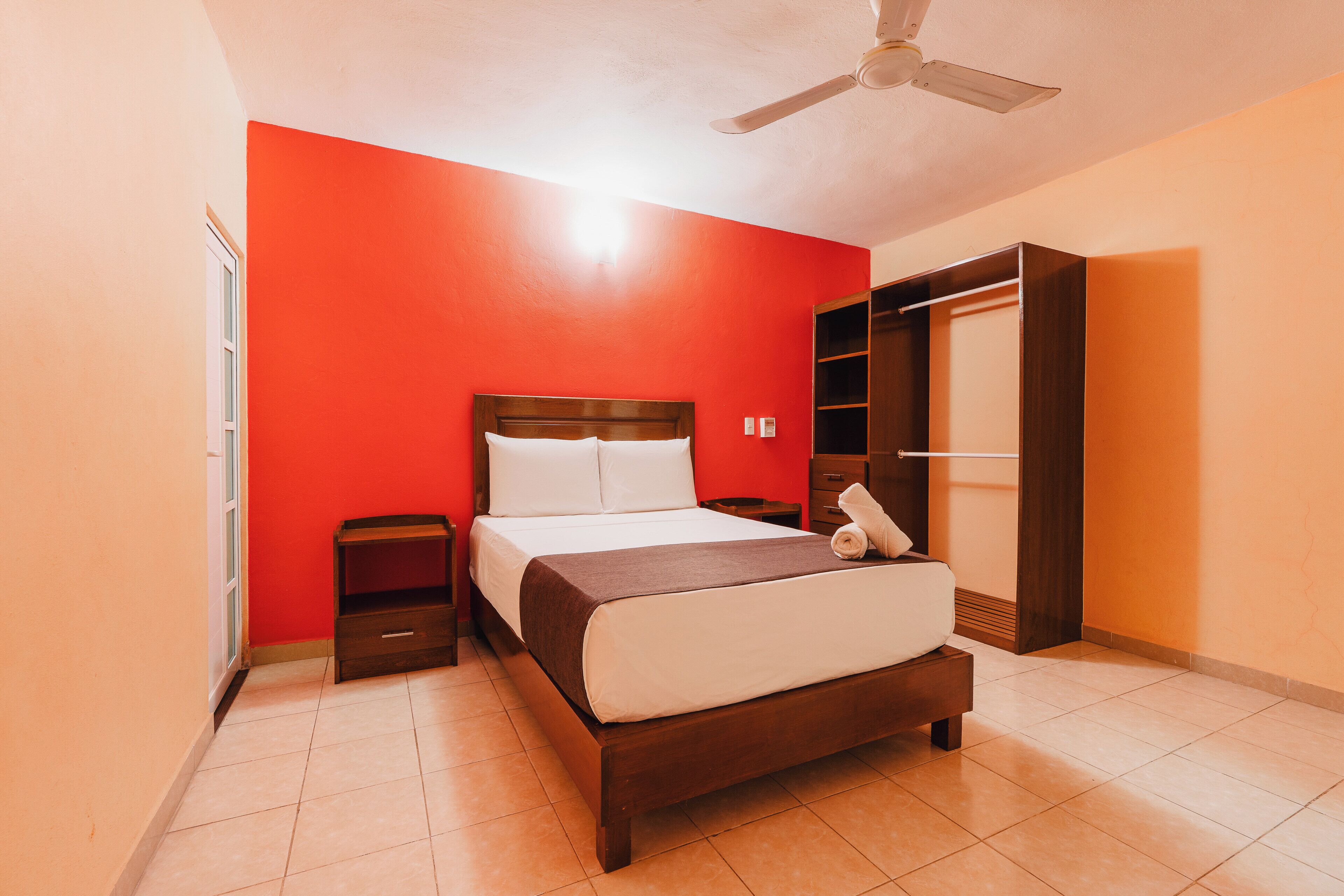 A bedroom with a bed, a nightstand, a wardrobe, and a ceiling fan.