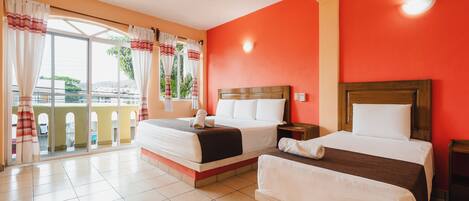 A hotel room with two beds, a balcony, a ceiling fan, and a red wall.