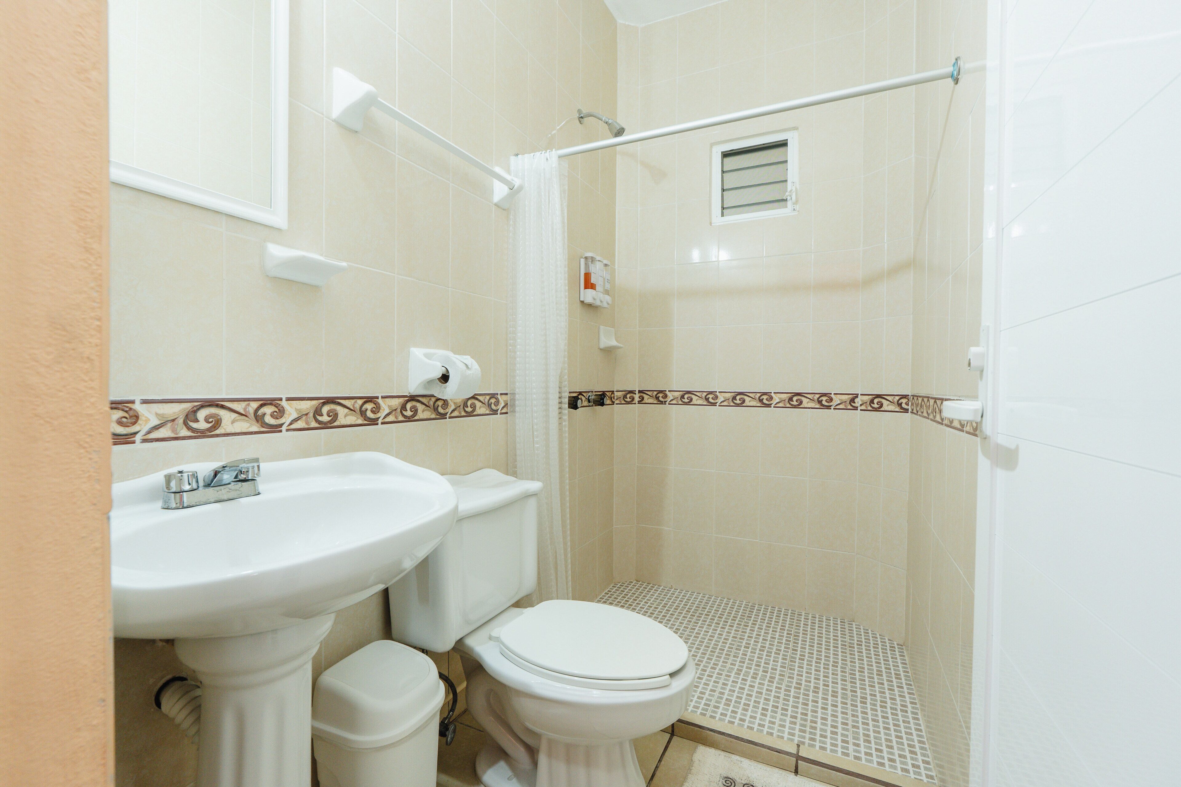A bathroom with a sink, toilet, shower, and a towel rack.