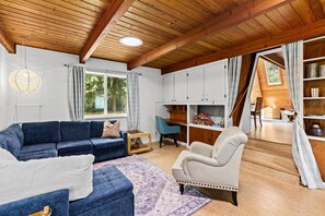 Un salon chaleureux avec un canapé bleu, un tapis à motifs et un plafond en bois.