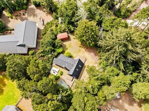 Luchtbeeld van een woongebied met meerdere huizen, weelderige begroeiing en een heldere lucht.