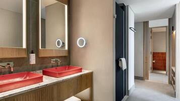 A modern bathroom with two red sinks, a large mirror, and a walk-in shower.