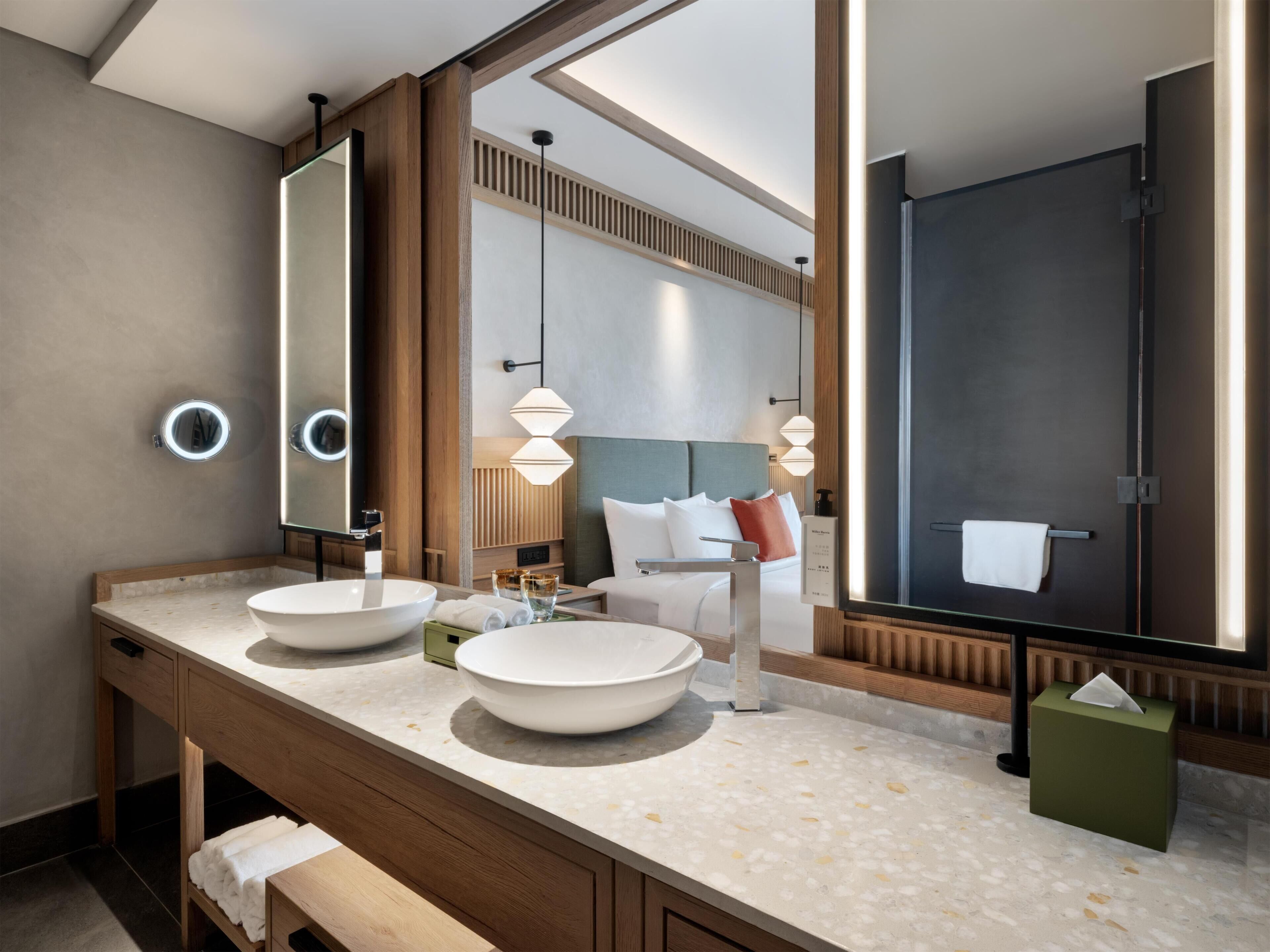 A modern bathroom with two sinks, a large mirror, and a bench.