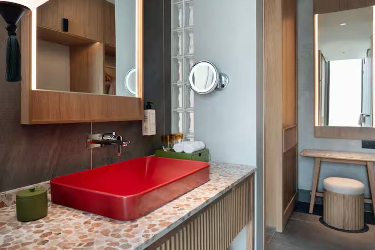 A bathroom with a red sink, a mirror, and a towel rack.