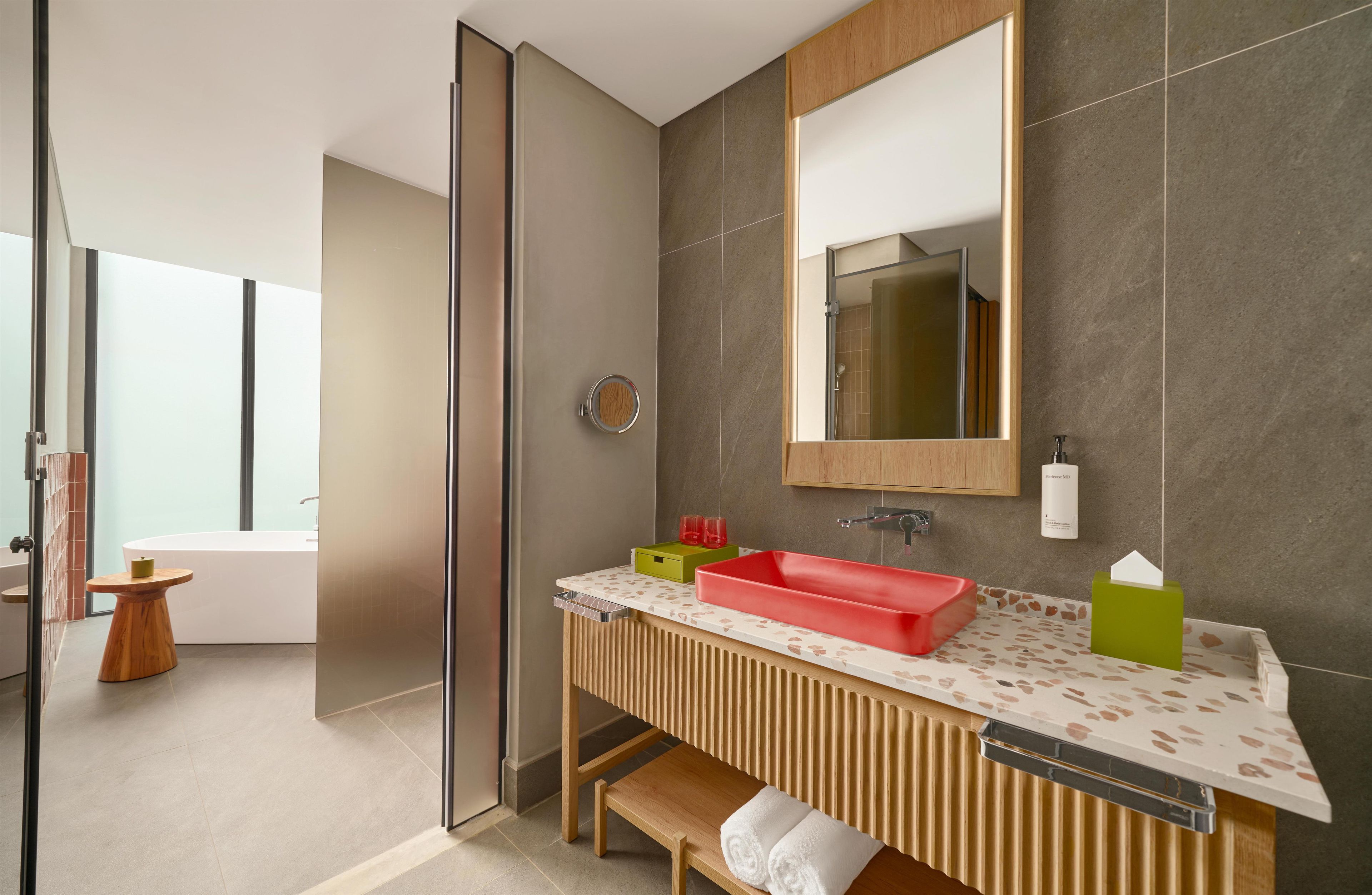 Een moderne badkamer met een houten wastafelmeubel, een grote spiegel en een rode wasbak.