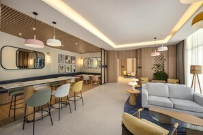 A modern hotel lobby with a bar area, seating, and a sofa. - Hampton By Hilton Jeddah Souq7 (Jeddah)