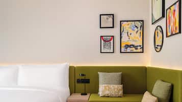 A hotel room with a bed, a green sofa, and artwork on the wall.