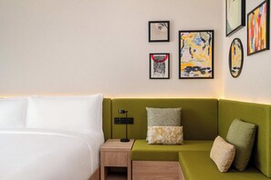 A hotel room with a bed, a green sofa, and artwork on the wall. - Hampton By Hilton Jeddah Souq7 (Jeddah)