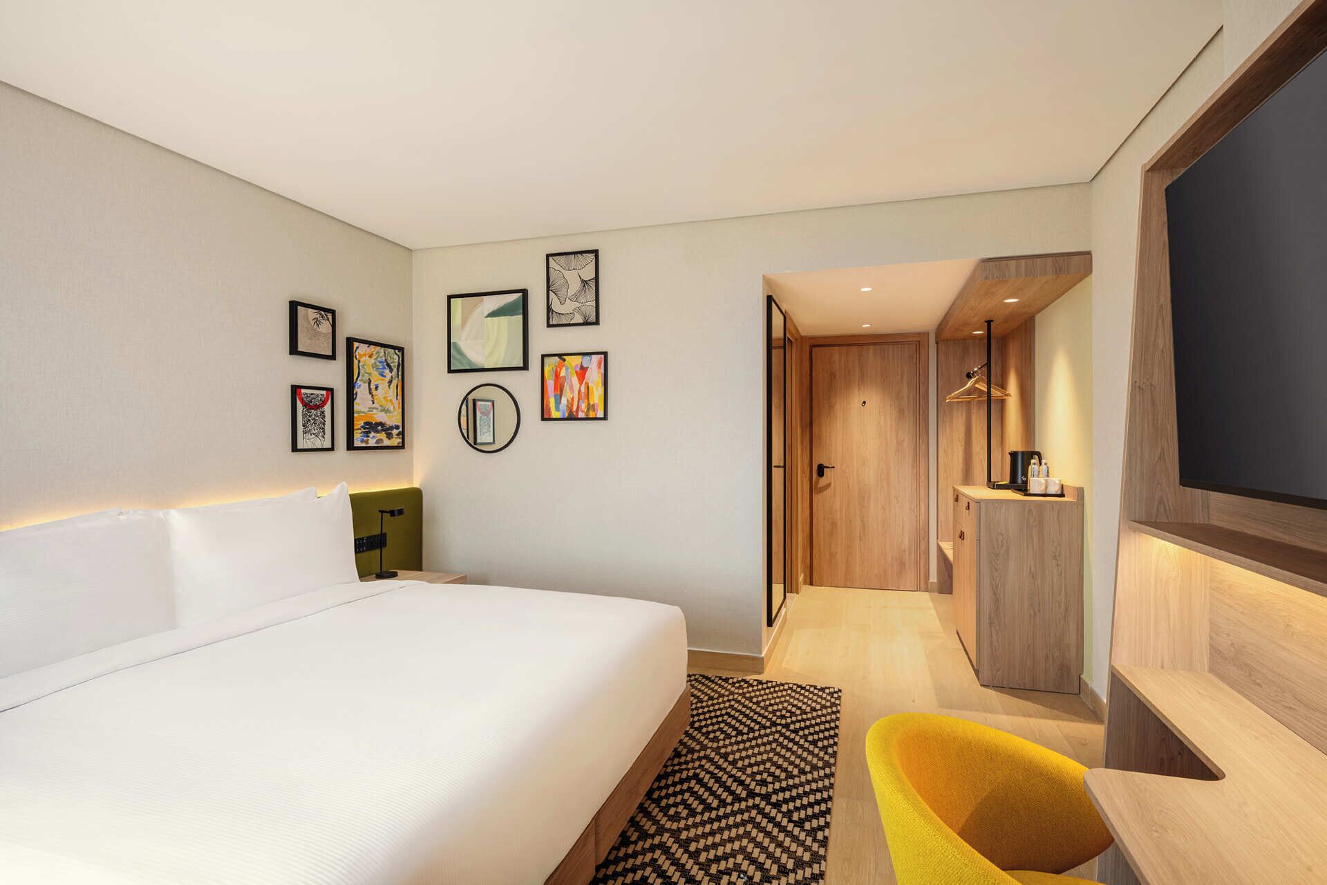 Ein Hotelzimmer mit einem großen Bett, einem Schreibtisch, einem Stuhl und einem Spiegel.