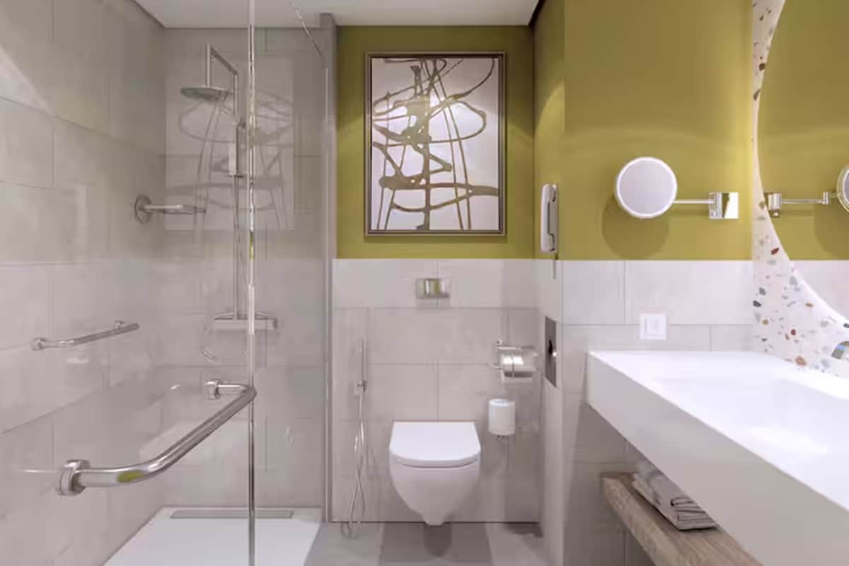 A modern bathroom with a glass shower enclosure, a toilet, and a sink with a mirror.
