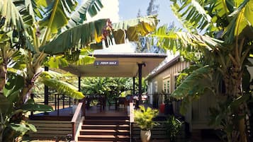 A covered outdoor area with a sign reading 'Farm Hale,' wooden steps leading to a covered seating area, and a potted plant.