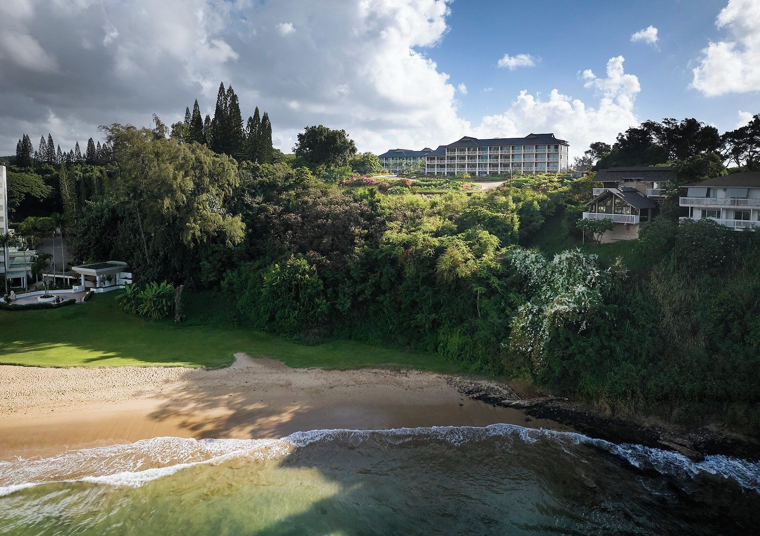 A coastal landscape with a sandy beach, a small stream, and a building complex in the background.
