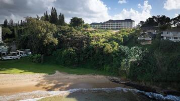A coastal landscape with a sandy beach, a small stream, and a building complex in the background.