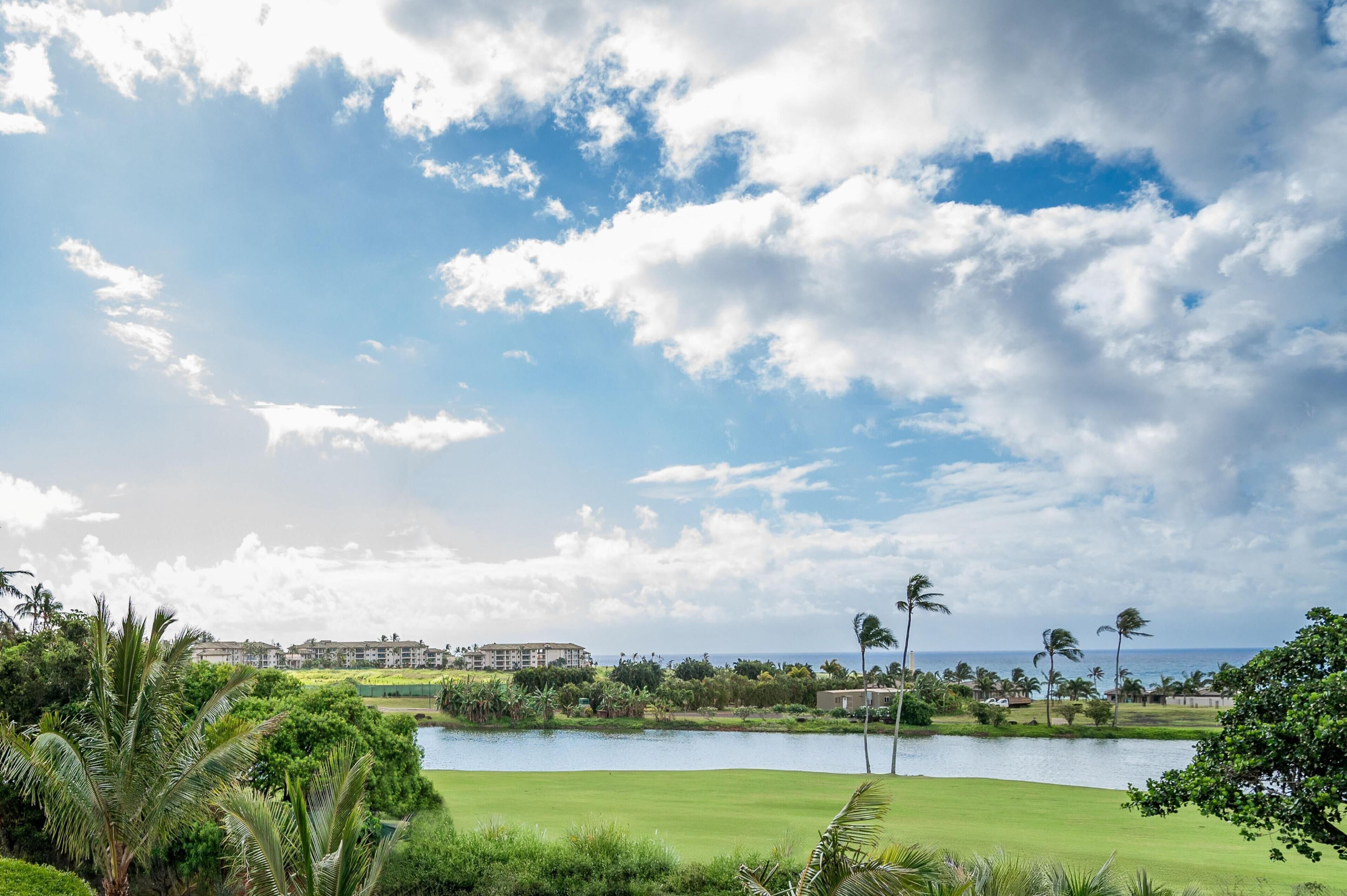 Un parcours de golf avec un étang, des palmiers et un bâtiment en arrière-plan.