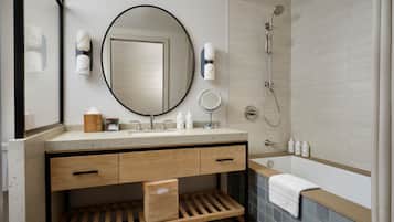 Un baño moderno con un espejo redondo grande, un lavamanos, una ducha y una bañera.