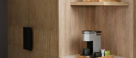 A kitchen area with a coffee machine, a red pot, and a tray with cups and a green tea box.
