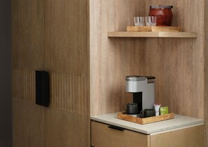 A kitchen area with a coffee machine, a red pot, and a tray with cups and a green tea box.