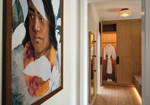 Een hal met een houten garderobe, een badjas aan de deur en een gekaderd schilderij aan de wand.