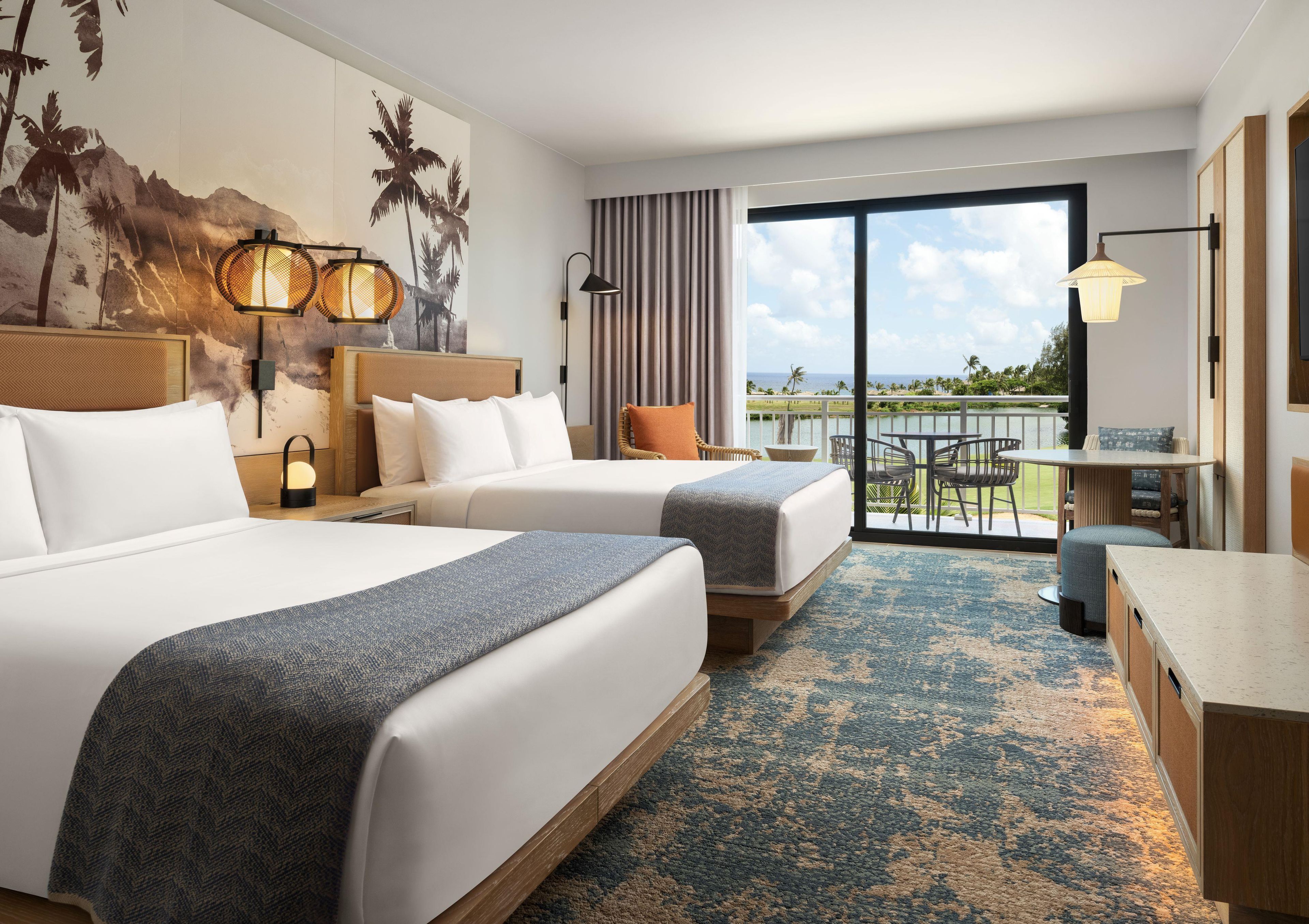 Quarto de hotel com duas camas, varanda e área de refeições.