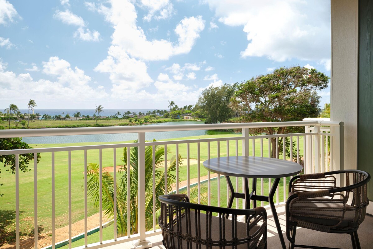 Een balkon met uitzicht op een golfbaan en een wateroppervlak.