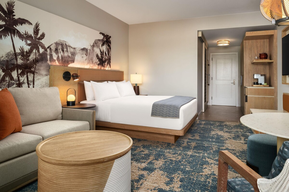 Een hotelkamer met een bed, een bank, een ronde tafel en een televisie aan de muur.