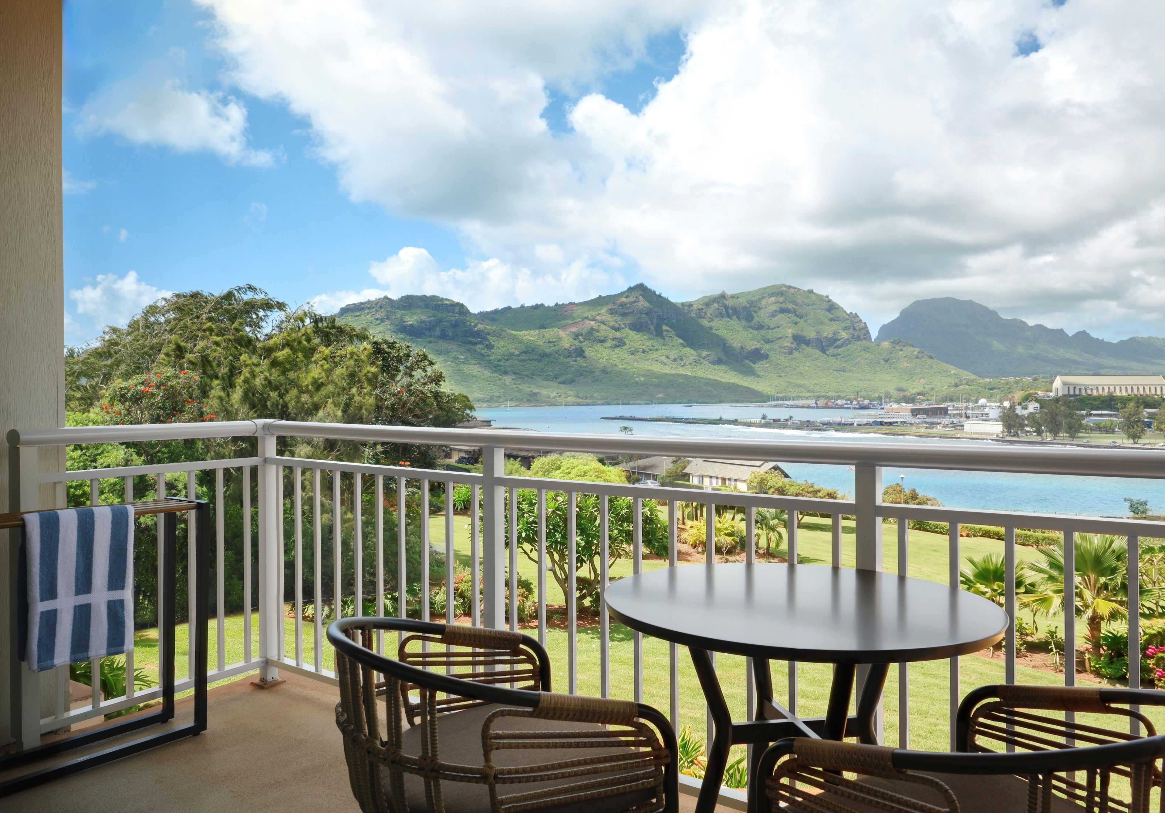 A balcony with a view of a coastal landscape, including mountains and a body of water.