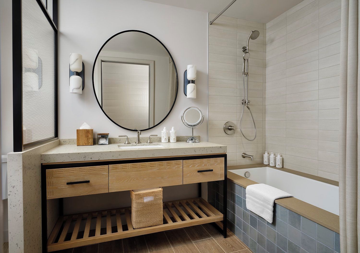 A modern bathroom with a large round mirror, a shower, and a bathtub.