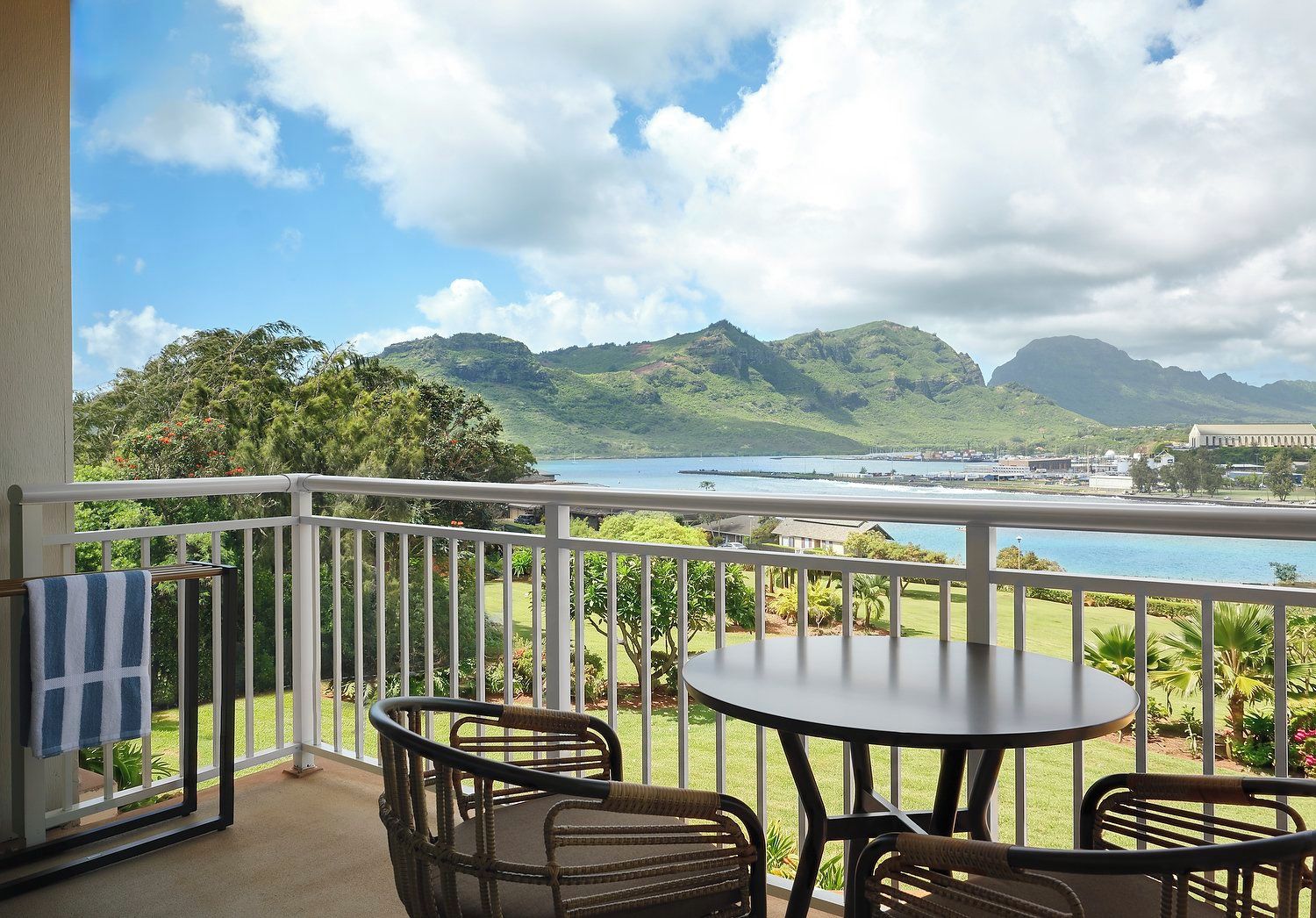 A balcony with a view of a body of water, greenery, and distant mountains.