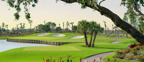 Un parcours de golf doté de bunkers de sable, d’un plan d’eau et d’un sentier bordé d’arbres.