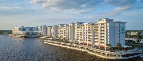 Un hôtel situé au bord de l’eau, composé de plusieurs bâtiments, doté de balcons et d’un quai.